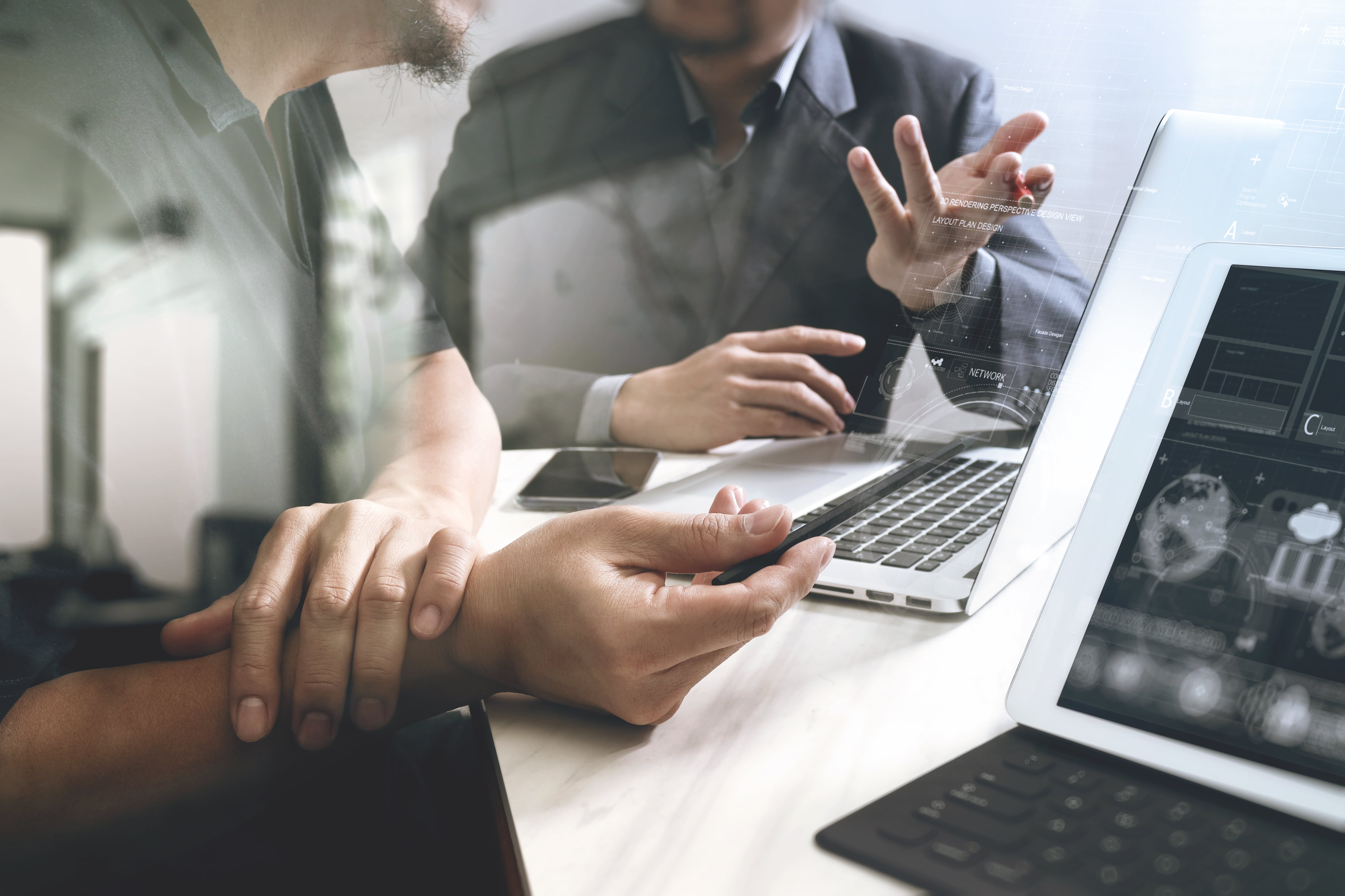 Picture of two business people discussing strategy in front of laptops.